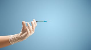 Female doctor hand holding syringe with blue background